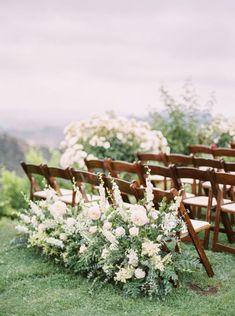 an outdoor ceremony set up with wooden chairs and flowers