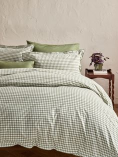 a green and white checkered comforter set on a bed with pillows, pillow cases and