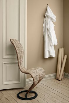 a chair sitting next to a coat rack in a room with beige walls and wooden floors