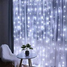 a living room with white curtains and lights on the window curtain is decorated with a plant