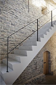 a stone building with stairs leading up to the second floor and an open door on one side