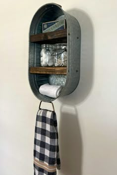 a towel hanging on the wall next to a shelf filled with jars and other items