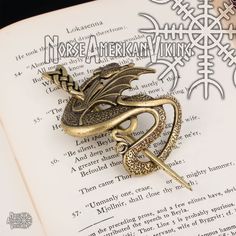 a golden dragon brooch sitting on top of an open book