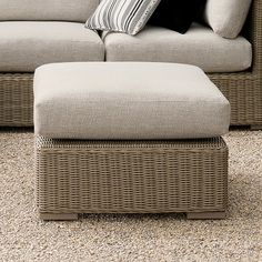 a wicker couch and footstool in a living room with carpeted flooring