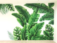 a painting of green leaves on a wall in a room with white walls and flooring