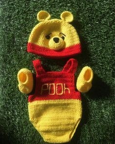 a crocheted winnie the pooh bear hat and diaper cover laying on grass