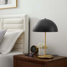 a bedroom with a bed, night stand and lamp on top of the nightstand next to it