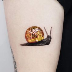 a snail on the side of a woman's thigh with an orange and white mosaic design