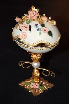 an ornate white vase with flowers on it's base and gold trimmings