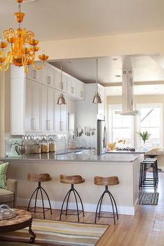 a kitchen with stools and a bar in the middle, next to an open floor plan