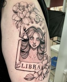 a woman's arm with a tattoo on it that says libra and flowers