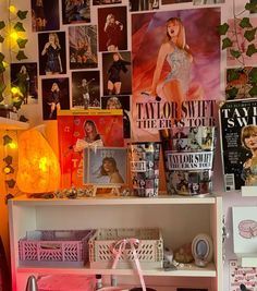 there are many pictures on the wall above this book shelf and in front of it is a pink purse