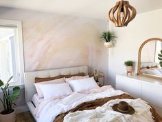 a bed room with a neatly made bed next to a mirror and potted plants