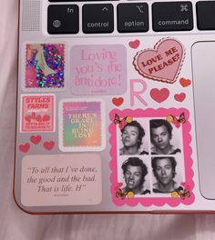 an open laptop computer with stickers on the keyboard and some writing in pinks