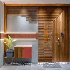 a modern entry way with wooden slats on the wall and potted plant next to it