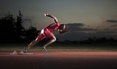 a man in red shirt and shorts doing a trick on a race track at night