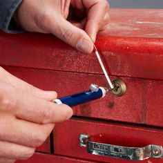 a person is opening a red box with a blue handle and a small screwdriver