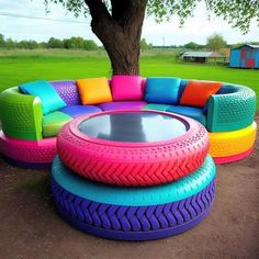 an unusual couch made out of old tires and other colorful furniture in a park setting