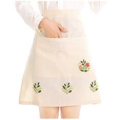 a woman wearing an apron with embroidered flowers on the front and side, holding her hands in