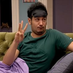 a man sitting on top of a couch making the peace sign