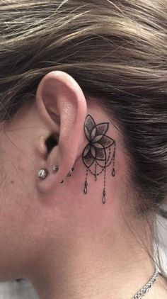 a woman's behind the ear has a tattoo on her left side, which is decorated with beads