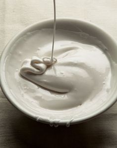 a white bowl filled with whipped cream on top of a wooden table