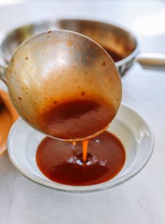 a sauce being poured into a white bowl