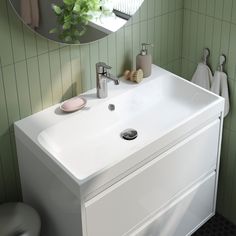 a white sink sitting under a bathroom mirror next to a green tiled wall and floor