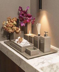 a bathroom sink with soap dispensers, candles and flowers on the counter