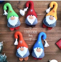 several felt gnomes sitting on top of a wooden table next to christmas ornaments and decorations