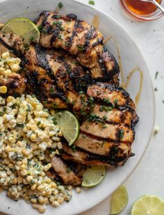 grilled chicken, corn and limes on a white plate