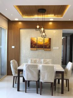 a dining room table with white chairs and a painting on the wall