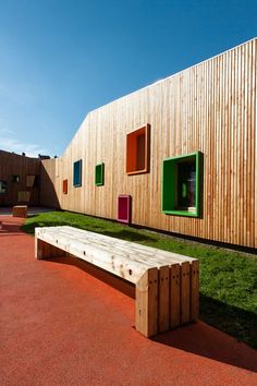 a wooden bench sitting in front of a building with green shutters on the windows