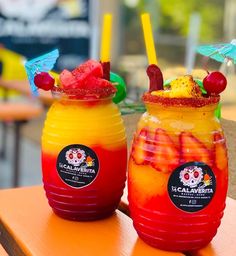 two colorful drinks sitting on top of a wooden table