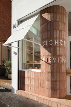 a sign for a bakery on the side of a building with glass doors and windows