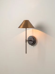 a wall light with a lamp on it in the corner next to a white wall