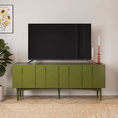 a flat screen tv sitting on top of a green cabinet next to a potted plant