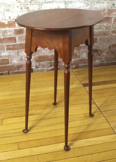 a small wooden table sitting on top of a hard wood floor next to a brick wall