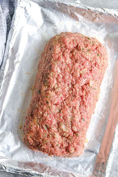 raw ground beef on aluminum foil with carrots and seasoning next to it, ready to be cooked