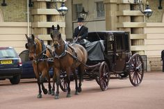 two brown horses pulling a carriage with a man in top hat on the front and side