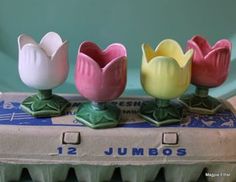 three plastic tulips sitting on top of an egg carton