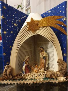 the nativity scene is made out of an open book and decorated with gold stars