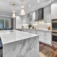 a kitchen with marble counter tops and stainless steel appliances, along with an island in the middle