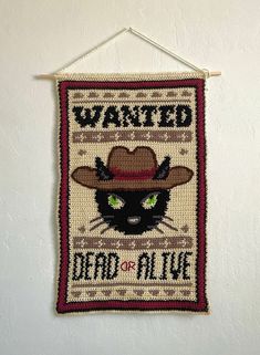 a wall hanging with a cat wearing a cowboy hat and the words wanted dead or alive on it