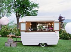 an old camper is parked in the grass with flowers on it's windows