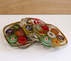 three glass trays filled with assorted bottle caps on top of a white table