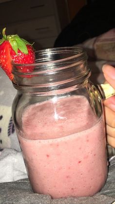 a person is holding a strawberry in a jar