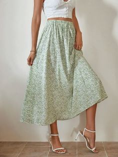 a woman wearing a white top and green floral print skirt with high heeled sandals