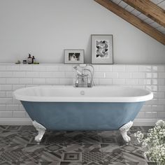 an old fashioned bathtub in a white bathroom with black and grey floor tiles on the walls