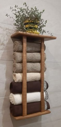 a wooden shelf with towels and a potted plant on it, hanging from the wall